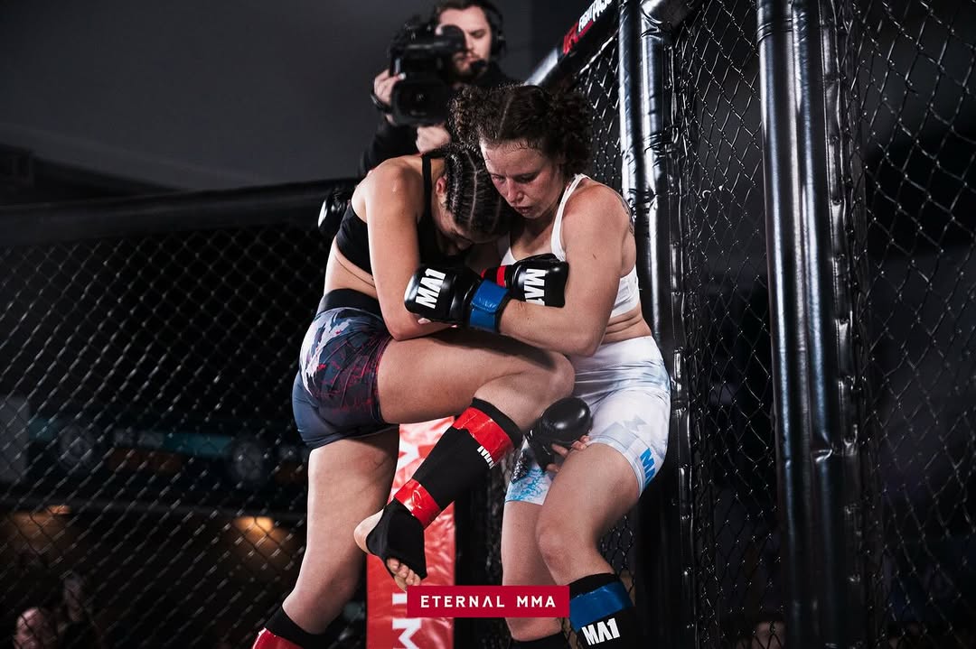 Ana Arvan in a clinch exchange against the cage